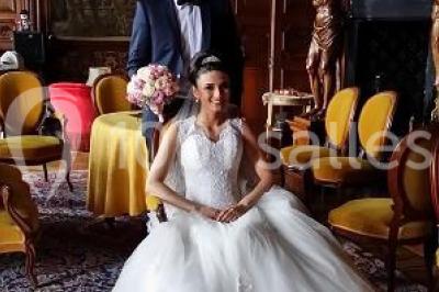 Allée bordée de sacs blancs menant à une tente blanche dans un parc verdoyant par temps ensoleillé.