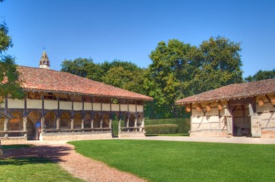 Miniature Location salle Saint-Cyr-sur-Menthon (Ain) - Domaine des Saveurs - Les Planons #7 Cour pavée avec un petit arbre au centre, entourée de bâtiments et de haies verdoyantes sous un ciel dégagé.