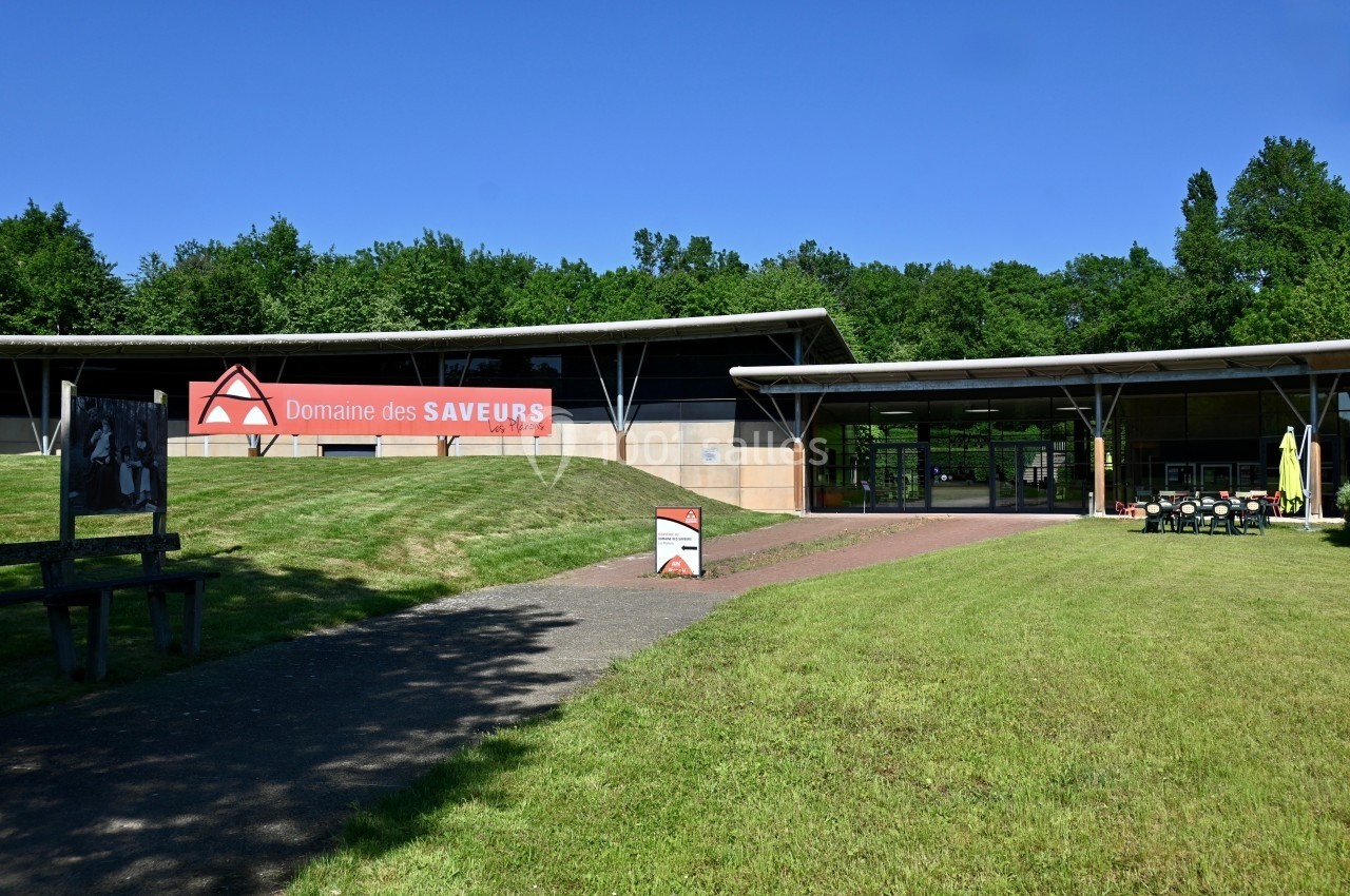 Façade d'un bâtiment moderne entouré de pelouses, avec un panneau indiquant ’Domaine des Saveurs’.