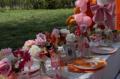 Salle de réception élégante avec tables rondes décorées de nappes blanches, chaises dorées et centres de table fleuris.