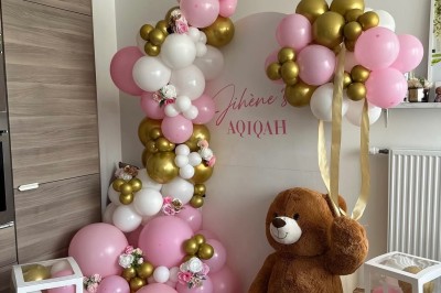 Salle de réception élégante avec tables rondes décorées de nappes blanches, chaises dorées et centres de table fleuris.