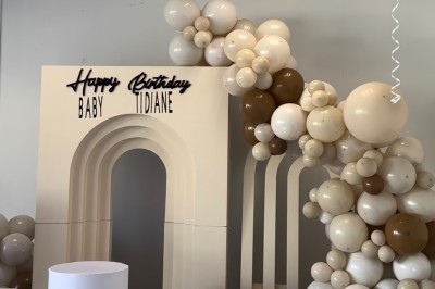 Salle de réception élégante avec tables rondes décorées de nappes blanches, chaises dorées et centres de table fleuris.