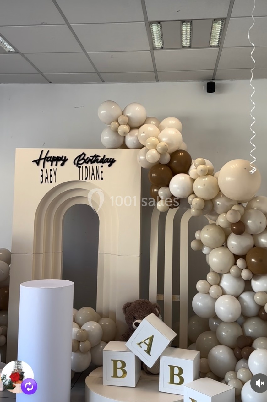 Décoration d'anniversaire avec arche blanche, ballons beige et marron, cubes décoratifs et inscription ’Happy Birthday Baby…