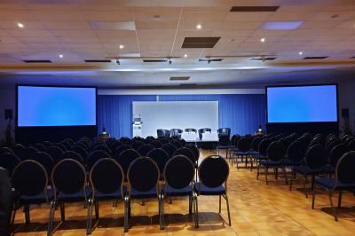 Un couloir d'exposition avec stands éclairés, affiches, et équipements audio sous un plafond voûté en bois.