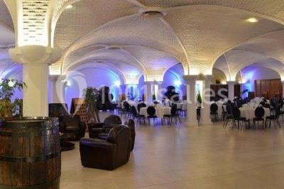 Un couloir d'exposition avec stands éclairés, affiches, et équipements audio sous un plafond voûté en bois.