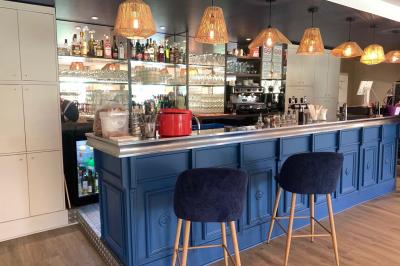 Terrain de pétanque miniature avec tapis bleu, entouré d'herbe, et boules rangées dans des supports aux extrémités.