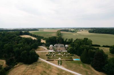 Une mariée en robe longue marche aux côtés d'un homme en costume sur une terrasse avec vue sur un paysage verdoyant.