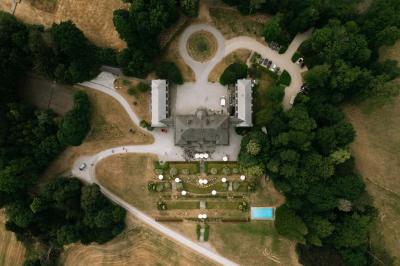 Une mariée en robe longue marche aux côtés d'un homme en costume sur une terrasse avec vue sur un paysage verdoyant.