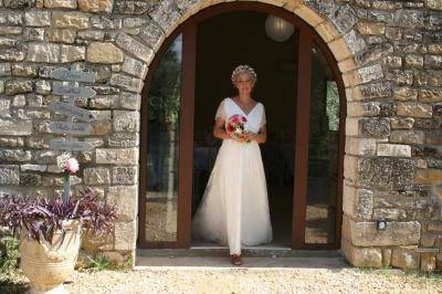 Salon lumineux avec canapé turquoise, coussins colorés, télévision, tapis en fibres naturelles et vue sur une cuisine…