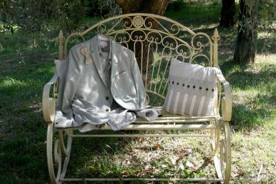 Salon lumineux avec canapé turquoise, coussins colorés, télévision, tapis en fibres naturelles et vue sur une cuisine…