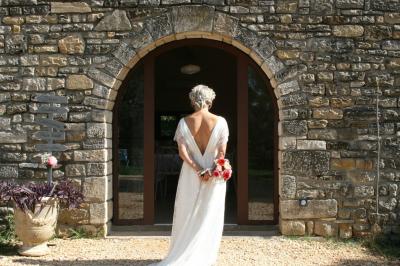 Salon lumineux avec canapé turquoise, coussins colorés, télévision, tapis en fibres naturelles et vue sur une cuisine…