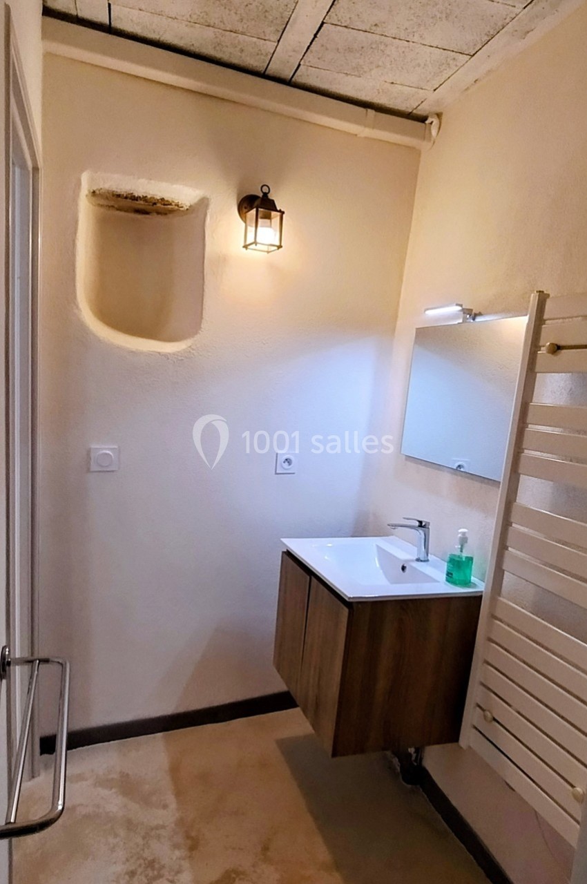 Salle de bain avec lavabo suspendu, miroir, applique murale, radiateur sèche-serviettes et niche murale.