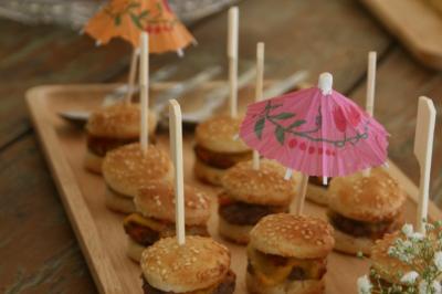 Salon lumineux avec canapé turquoise, coussins colorés, télévision, tapis en fibres naturelles et vue sur une cuisine…