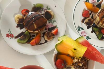 Salon lumineux avec canapé turquoise, coussins colorés, télévision, tapis en fibres naturelles et vue sur une cuisine…