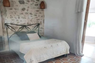 Salon lumineux avec canapé turquoise, coussins colorés, télévision, tapis en fibres naturelles et vue sur une cuisine…