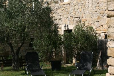 Salon lumineux avec canapé turquoise, coussins colorés, télévision, tapis en fibres naturelles et vue sur une cuisine…