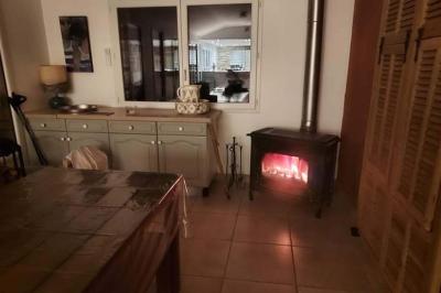 Salon lumineux avec canapé turquoise, coussins colorés, télévision, tapis en fibres naturelles et vue sur une cuisine…