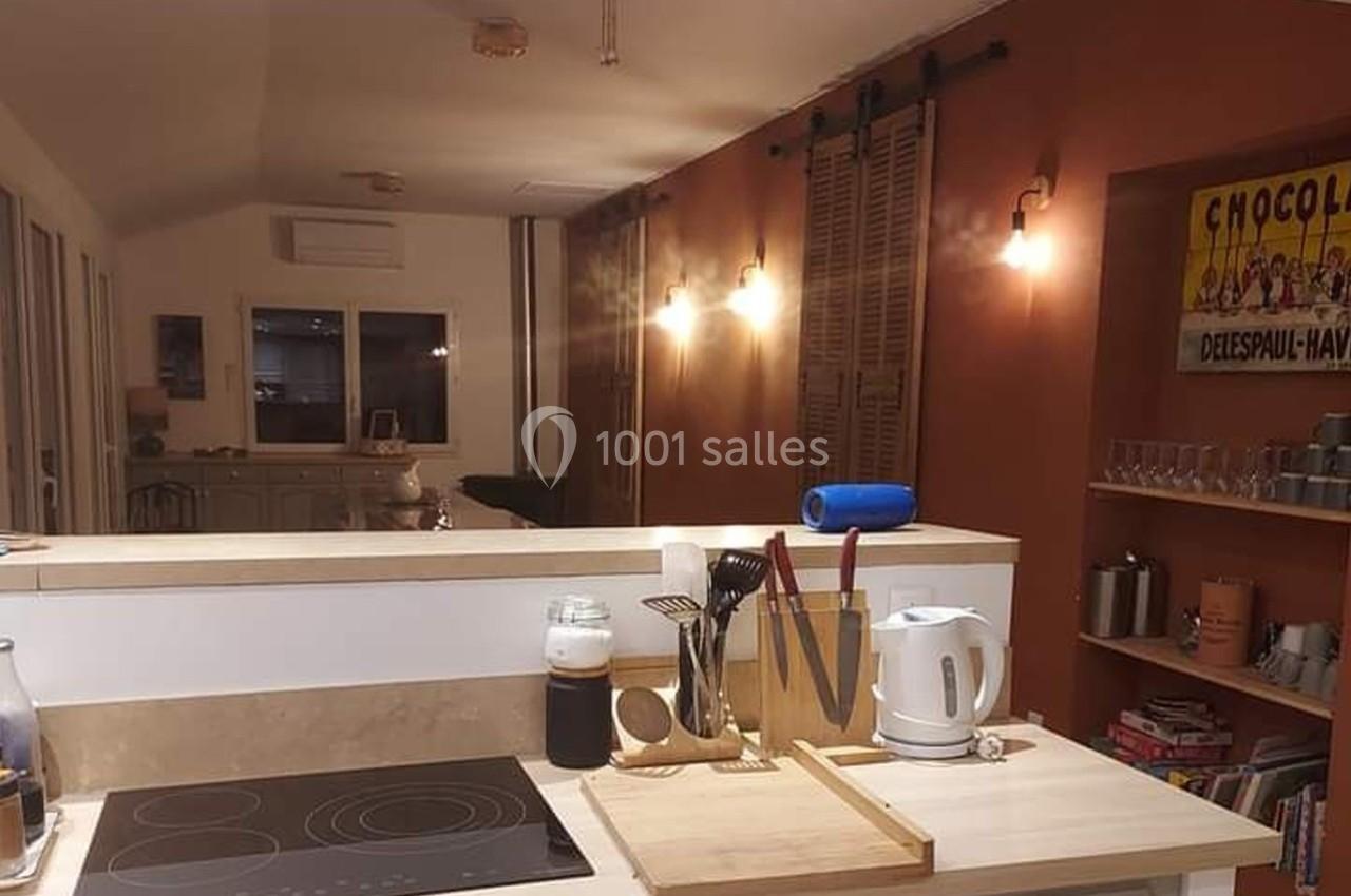 Cuisine ouverte avec plan de travail équipé, ustensiles, bouilloire et éclairage chaleureux dans un intérieur moderne.