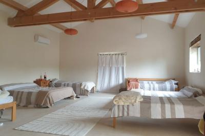 Salon lumineux avec canapé turquoise, coussins colorés, télévision, tapis en fibres naturelles et vue sur une cuisine…