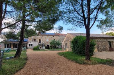 Salon lumineux avec canapé turquoise, coussins colorés, télévision, tapis en fibres naturelles et vue sur une cuisine…