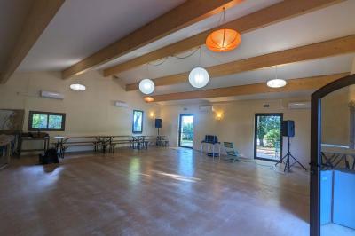 Salon lumineux avec canapé turquoise, coussins colorés, télévision, tapis en fibres naturelles et vue sur une cuisine…