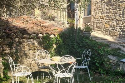 Salon lumineux avec canapé turquoise, coussins colorés, télévision, tapis en fibres naturelles et vue sur une cuisine…