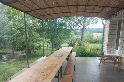 Salon lumineux avec canapé turquoise, coussins colorés, télévision, tapis en fibres naturelles et vue sur une cuisine…