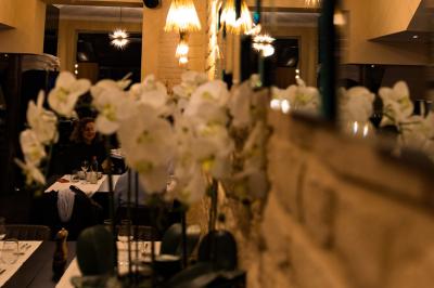 Salle de restaurant avec tables dressées, banquettes en bois, bar en bois et étagères garnies de verres et bouteilles.