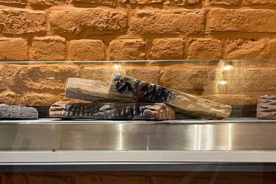 Salle de restaurant avec tables dressées, banquettes en bois, bar en bois et étagères garnies de verres et bouteilles.