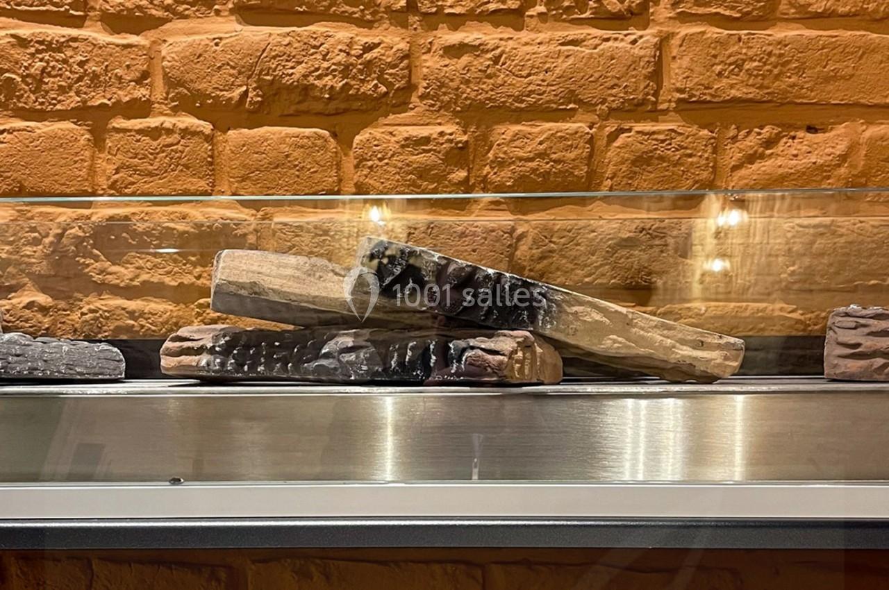 Briques en terre cuite exposées derrière une vitre, posées sur une étagère métallique devant un mur de briques.