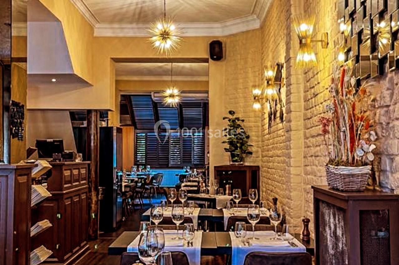 Salle de restaurant élégante avec tables dressées, éclairage chaleureux et murs en pierre apparente.