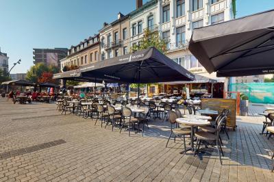 Salle de restaurant avec tables dressées, banquettes en bois, bar en bois et étagères garnies de verres et bouteilles.