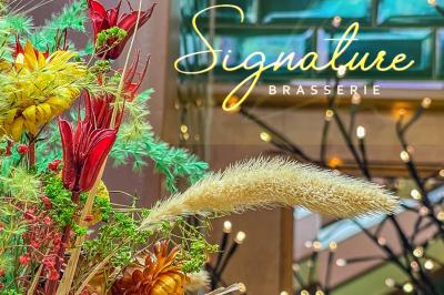 Salle de restaurant avec tables dressées, banquettes en bois, bar en bois et étagères garnies de verres et bouteilles.