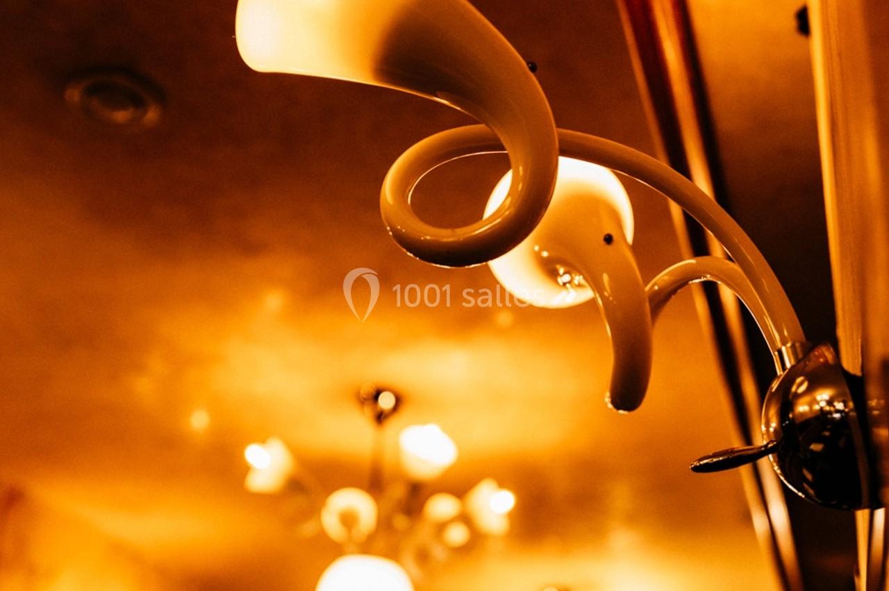 Applique murale blanche en forme de spirale éclairée, avec un plafond et d'autres luminaires en arrière-plan.