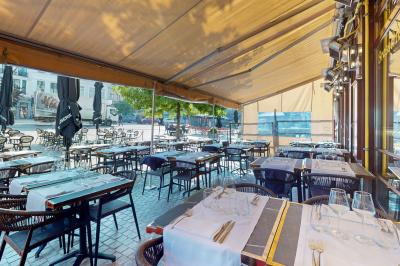 Salle de restaurant avec tables dressées, banquettes en bois, bar en bois et étagères garnies de verres et bouteilles.