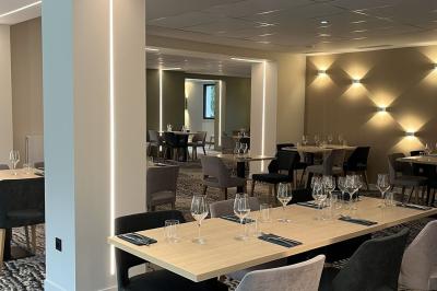 Lit avec des draps blancs, serviettes pliées au premier plan et mur décoré de branches et papillons colorés.