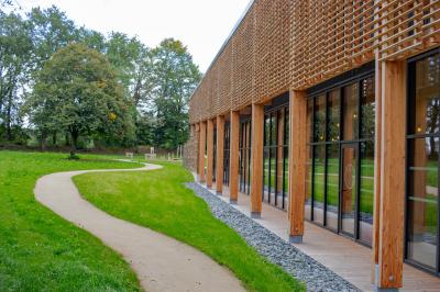 Lit avec des draps blancs, serviettes pliées au premier plan et mur décoré de branches et papillons colorés.