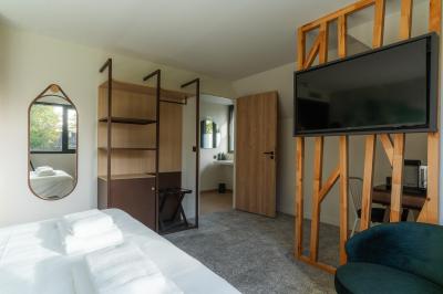 Lit avec des draps blancs, serviettes pliées au premier plan et mur décoré de branches et papillons colorés.