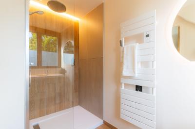 Lit avec des draps blancs, serviettes pliées au premier plan et mur décoré de branches et papillons colorés.