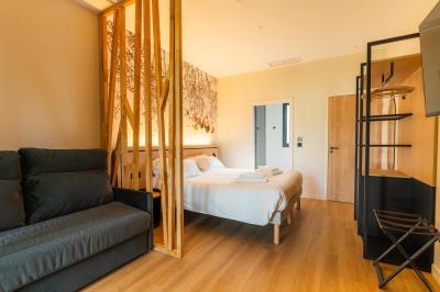 Lit avec des draps blancs, serviettes pliées au premier plan et mur décoré de branches et papillons colorés.