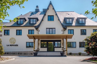 Lit avec des draps blancs, serviettes pliées au premier plan et mur décoré de branches et papillons colorés.