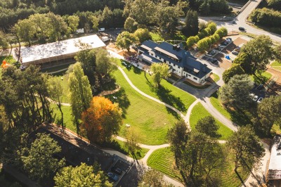 Tentes blanches modernes installées sur une pelouse verte devant un bâtiment avec terrasse, par une journée ensoleillée.