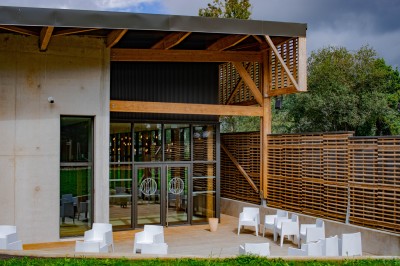 Tentes blanches modernes installées sur une pelouse verte devant un bâtiment avec terrasse, par une journée ensoleillée.