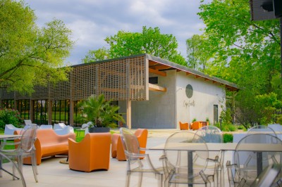 Tentes blanches modernes installées sur une pelouse verte devant un bâtiment avec terrasse, par une journée ensoleillée.