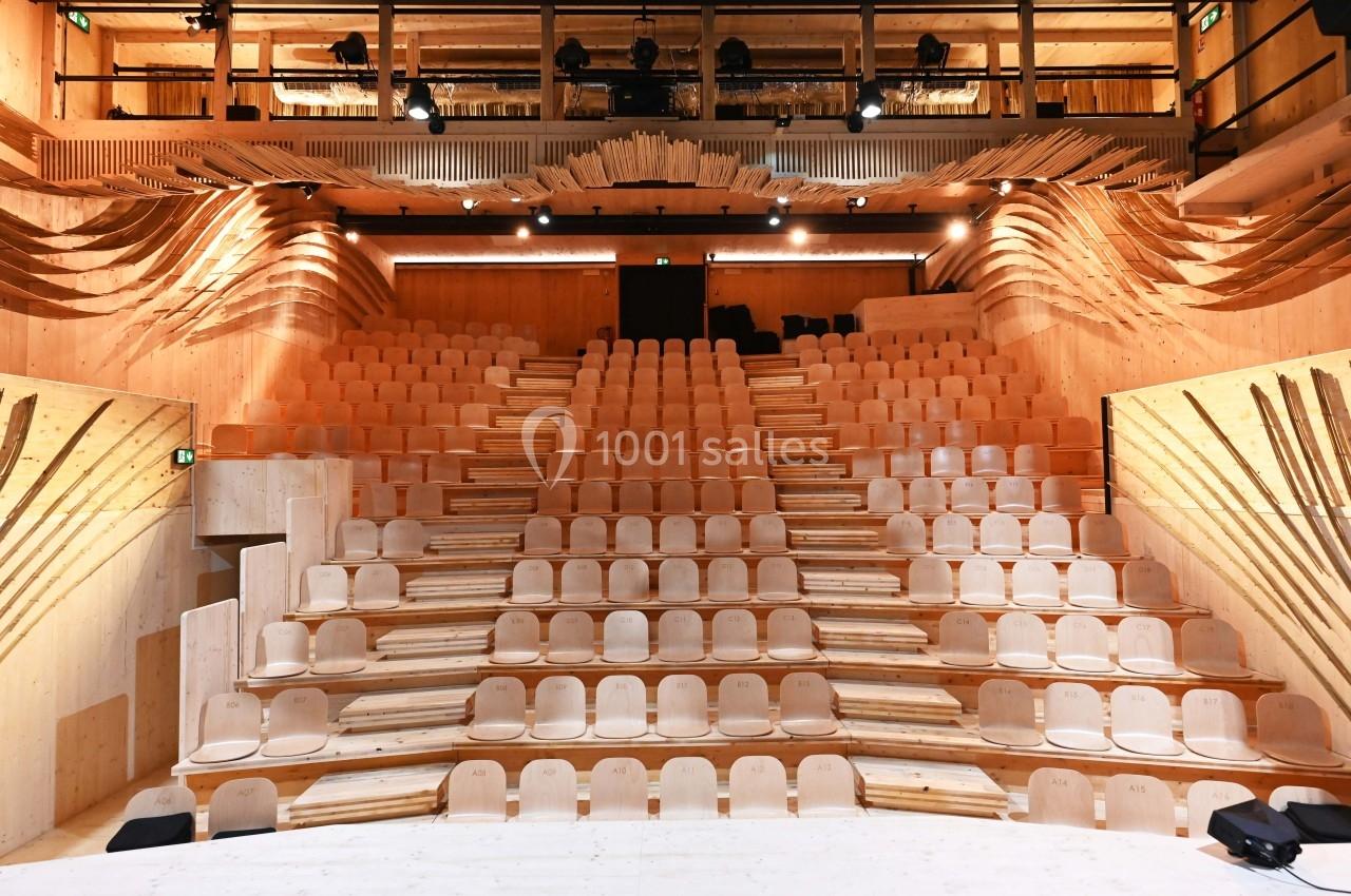 Salle de spectacle en bois avec gradins en escalier et éclairage intégré, vue depuis la scène.