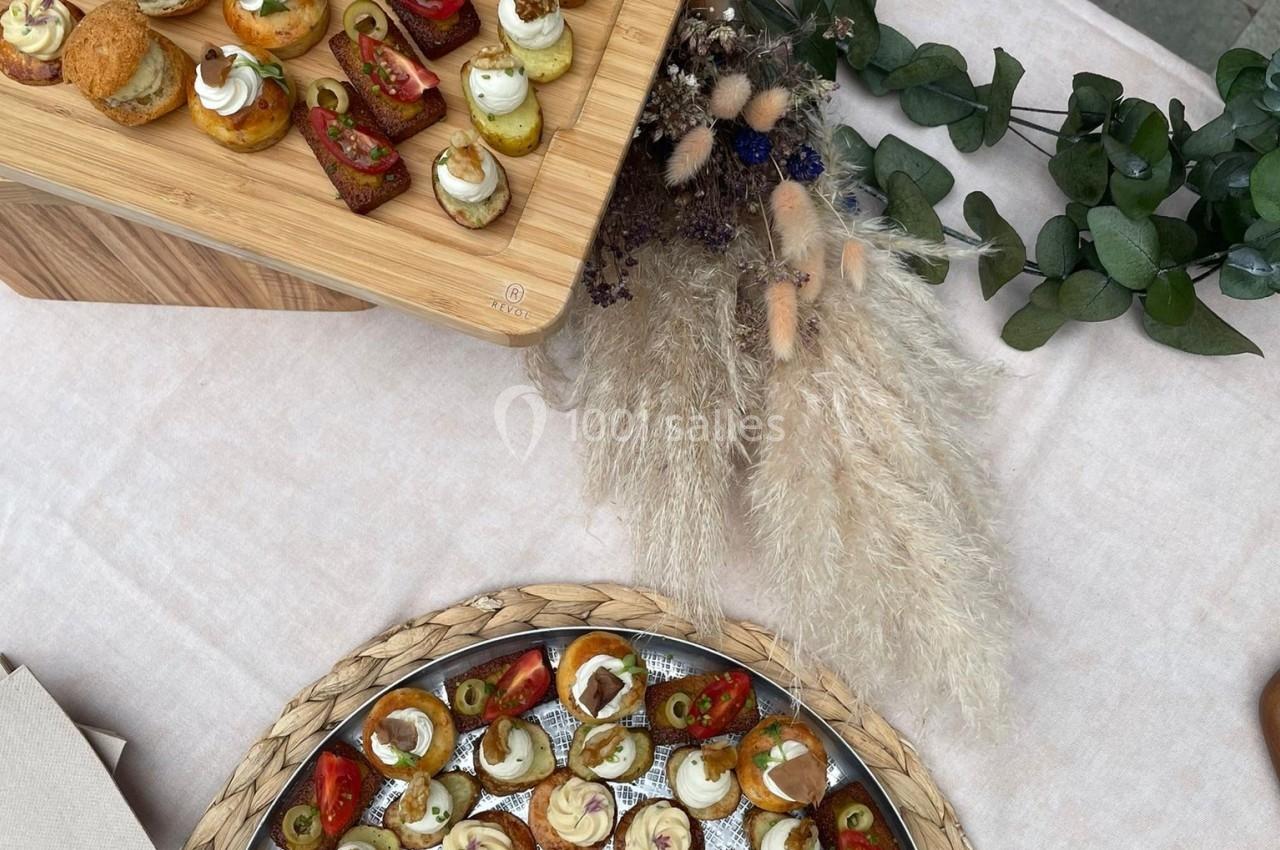 Plateaux de bouchées apéritives variées, disposés sur une table avec décoration végétale et pampas séchées.