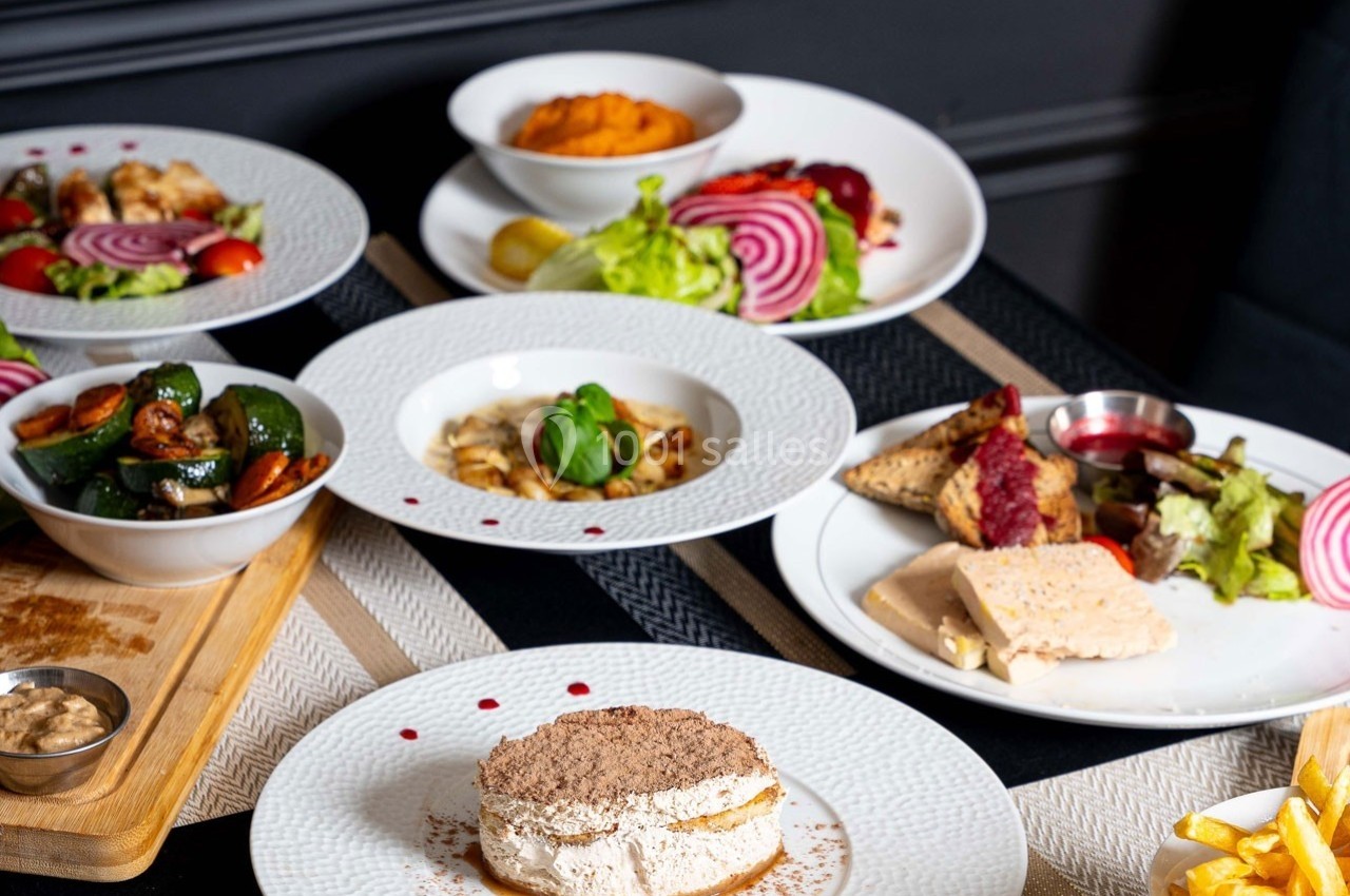 Assortiment de plats variés, incluant fromages, légumes, purée et viandes, présentés sur une table élégante.