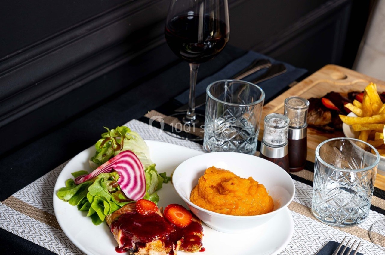 Assiette avec viande sauce rouge, purée de patate douce, salade verte et betterave, accompagnée d'un verre de vin rouge.