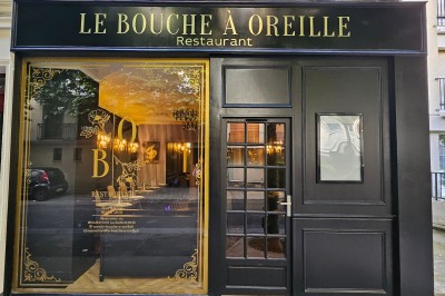 Logo du restaurant ’Le Bouche à Oreille’ avec des motifs floraux dorés sur fond noir.