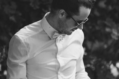 Homme en chemise blanche jouant de la batterie en extérieur, entouré de végétation.